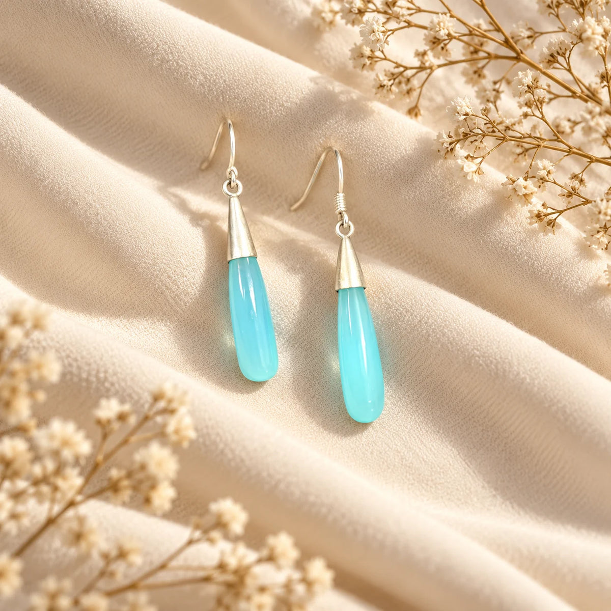 Silver plated hook earrings with a long polished blue stone drop. Ankkshi's Aakar collection.